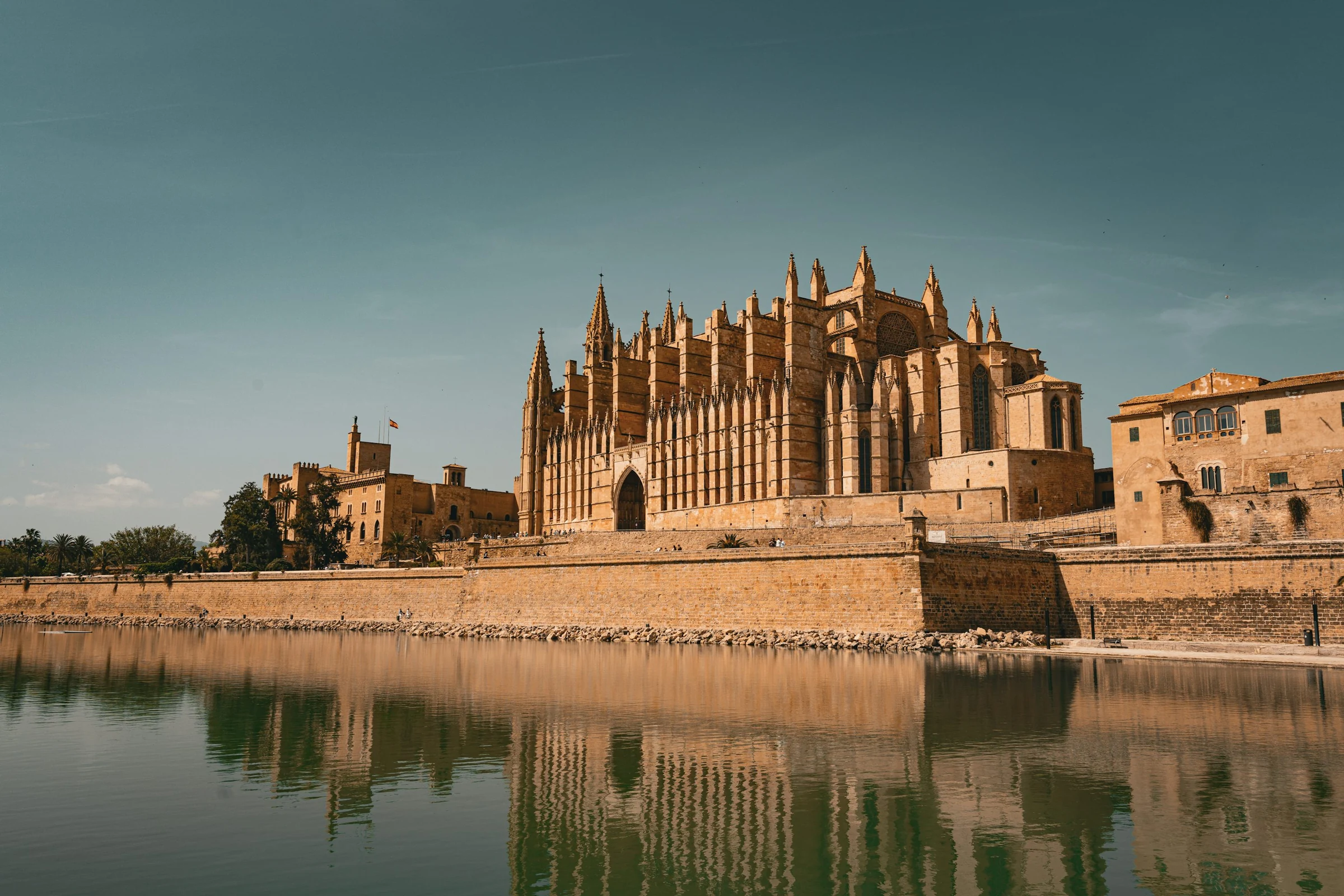 Palma Cathedral reflected in the waterfront pool beneath a clear sky