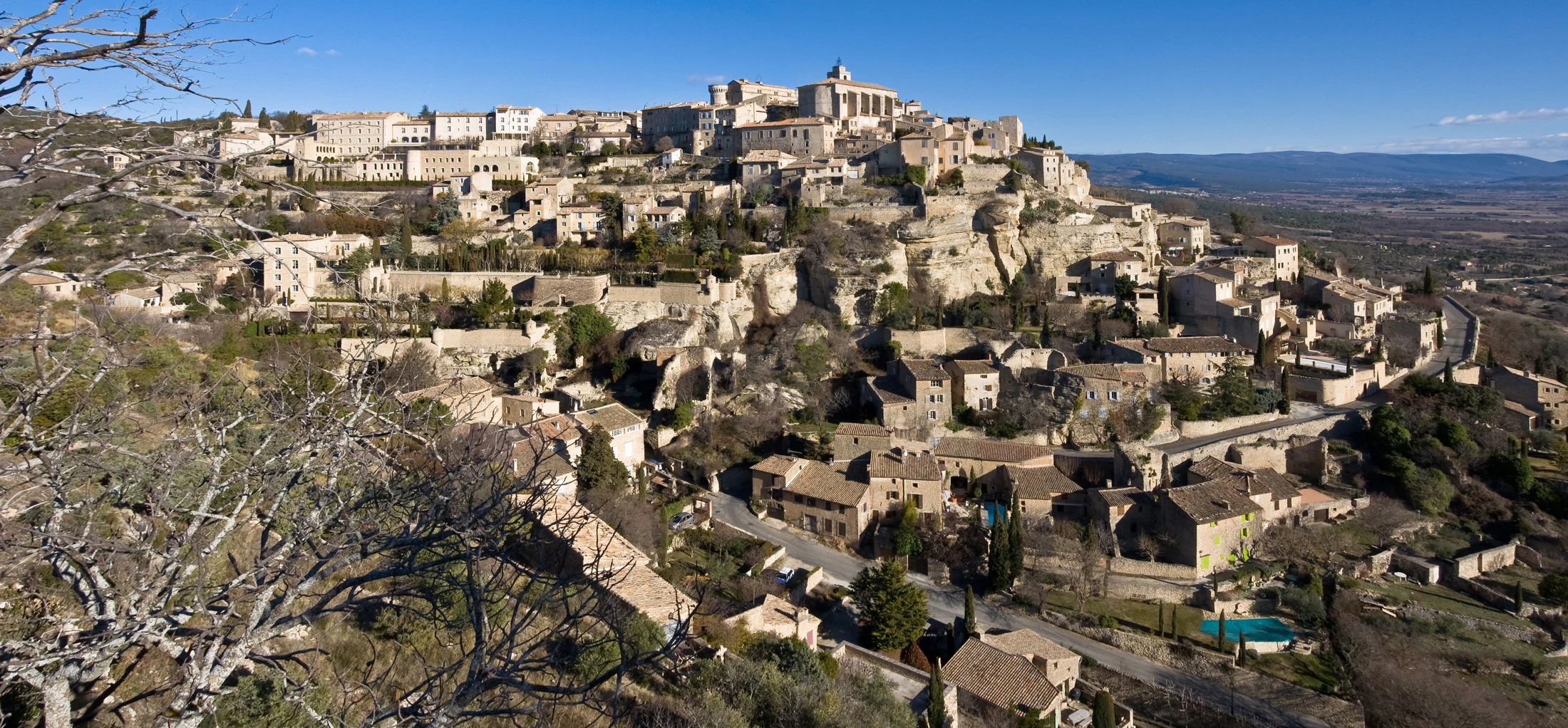 Stone buildings of Gordes rising above the wooded Provençal hillside